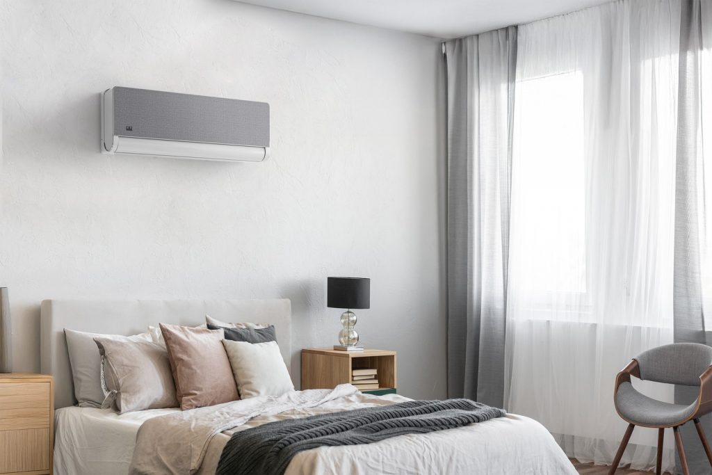Weiß-graues Split-Klimagerät an der Schlafzimmerwand über einem Bett in hellem Wohnambiente